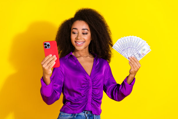 漂亮的年轻女孩的照片肖像拿着设备钱扇穿着时髦的紫罗兰装孤立在黄色的背景图片下载