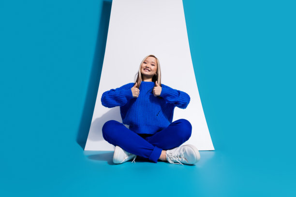 时尚的韩国女孩广告手机显示促进电子商务的照片显示大拇指孤立的蓝色背景图片下载