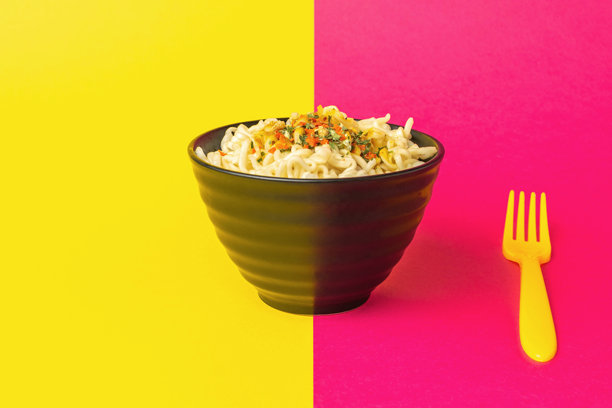 充满活力的面碗与黄色叉子在彩色背景图片下载