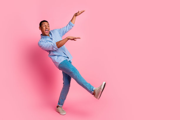 英俊的无忧无虑的家伙的全身照片穿格子衬衫走有乐趣的空间孤立的粉红色背景图片下载
