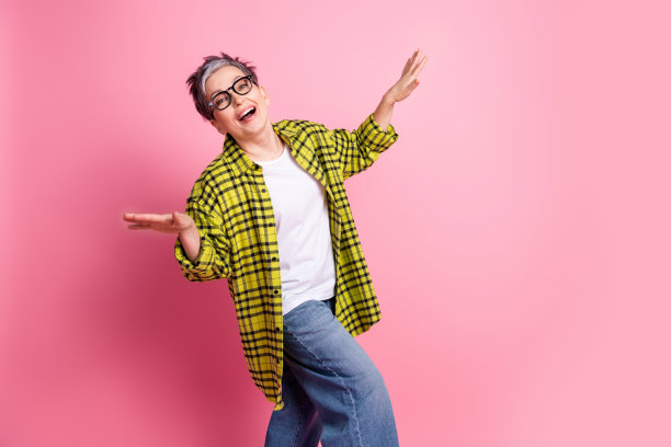 照片漂亮的老年妇女跳舞的格子衬衫孤立在粉红色的背景图片下载