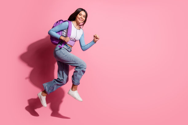 开朗积极的女学生的照片，女学生穿着时髦的衣服上学，在粉红色的背景上孤立的空间图片下载