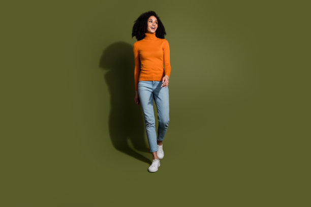 全长照片迷人的积极的女人穿橙色毛衣走路看空空间孤立的卡其色背景图片下载