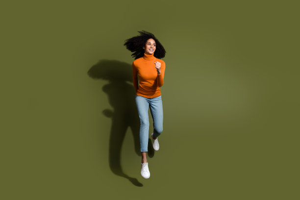 全身照片迷人的积极的女人穿橙色毛衣跳高走空空间孤立的卡其色背景图片下载