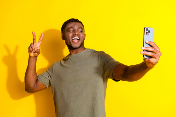 照片的开朗高兴的好男人穿着卡其布时尚的衣服谈话视频会议的v字孤立的黄色背景图片下载