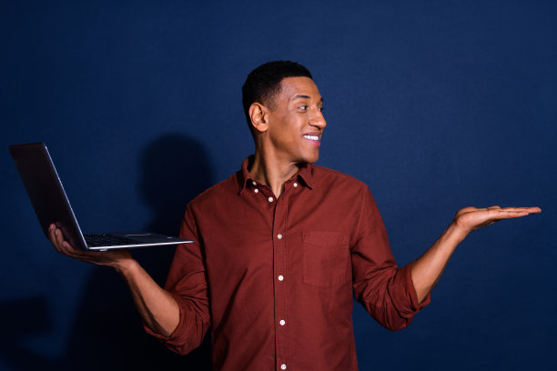 梦幻酷的家伙穿着棕色衬衫交流现代设备的照片，手臂空的空间孤立的蓝色背景图片下载