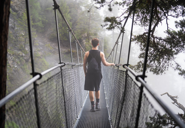 冒险的概念，一个人穿过悬索桥，看着远处。图片下载