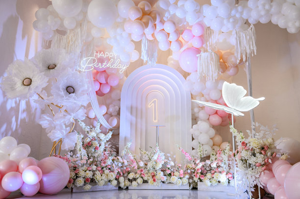 儿童照相区。背景照片墙上1岁女孩的生日派对。粉红色的拱门装饰，白色的气球，生日快乐的文字，鲜花，蝴蝶纸装饰。图片下载
