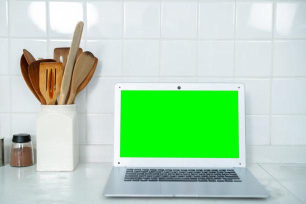 绿色屏幕上的笔记本电脑模型糖，玻璃罐里的香料鸡蛋，蔬菜，西红柿和厨房白色桌子上的搅拌器。平的。食物准备的概念，背景介绍。图片下载