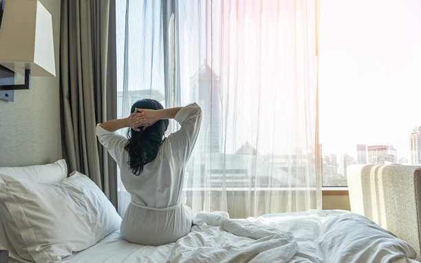 亚洲女性慵懒的一天在酒店放松，周末早上从床上睡个好觉醒来，在舒适的卧室里休息，享受快乐的工作与生活质量平衡的生活方式图片下载