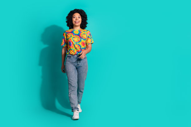 全长照片迷人的积极的女人穿印花t恤走空空间孤立的蓝绿色背景图片下载