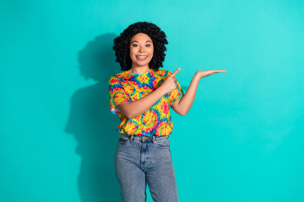 照片正面迷人的女人穿着时尚的衣服展示了青色背景上孤立的空白空间图片下载