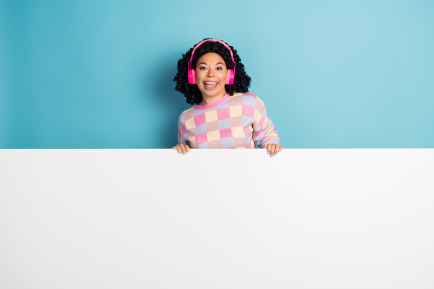 漂亮的年轻女孩的照片肖像耳机白色空白空间穿时髦的粉红色格子装孤立的蓝色背景图片下载