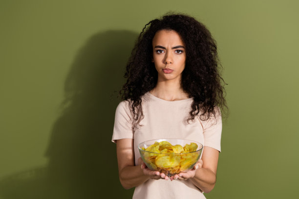 照片上困惑、忧郁、不满的女孩，波浪发型，穿着米色t恤，在卡其色背景上给你孤立的芯片图片下载