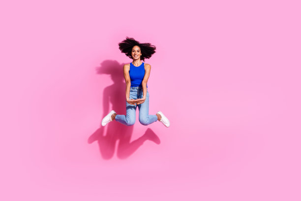 迷人的年轻女子全身照片跳优雅的飞行穿着时尚的蓝色衣服孤立在粉红色的背景图片下载