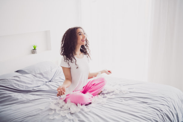 全身照片迷人的年轻女子坐在床上兴奋羽毛早上好振动醒来家卧室光白色的内部图片下载