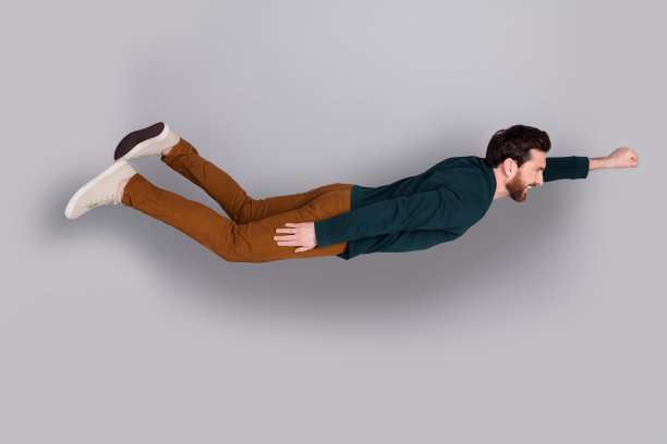 照片中风趣开朗有魅力的男人穿着时髦的绿色衣服飞空空间孤立在灰色的背景图片下载