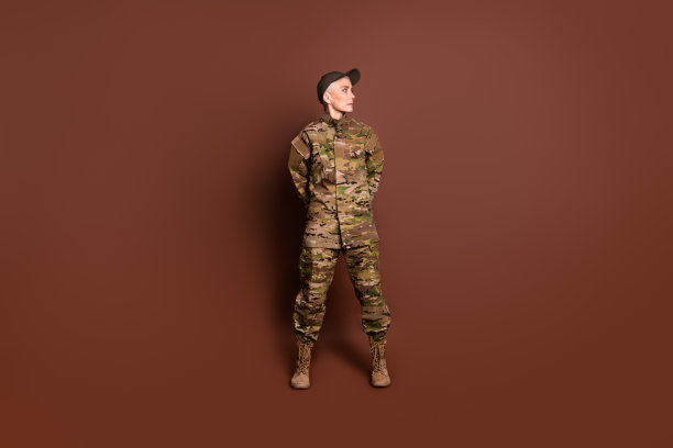 成熟的女兵的全身照片看起来空空洞洞的双手在背后穿着军服孤立的棕色背景图片下载