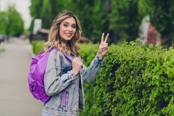 漂亮的年轻女子的个人资料照片背包显示v字穿着牛仔夹克走市中心户外图片下载