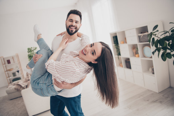 有吸引力的快乐已婚年轻夫妇的照片丈夫抱着妻子玩得开心花空闲时间搬新公寓，家室内室内图片下载