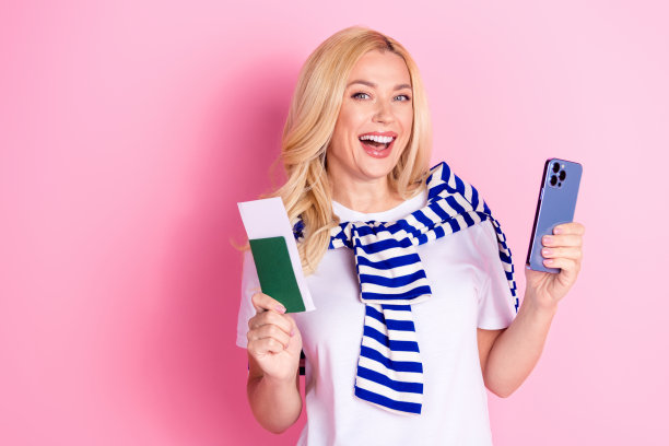 照片中，年轻漂亮的小女孩手持护照，穿着时髦的白色服装，背景是粉红色图片下载