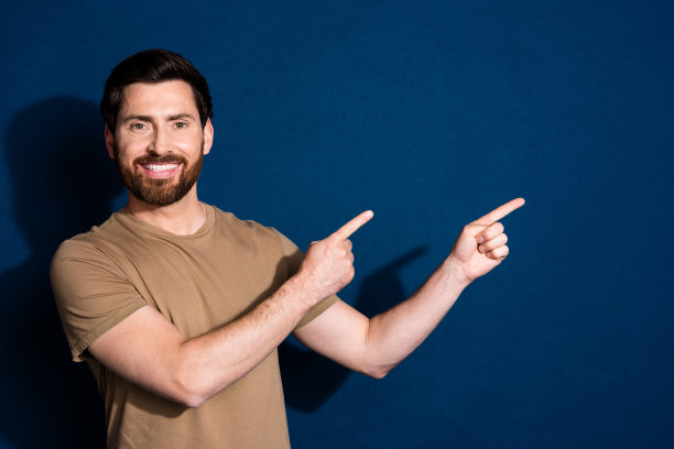 穿着米色t恤、长着牙齿、笑容满面的胡子男子的照片，在深蓝色的背景下，凝视着空白处图片下载