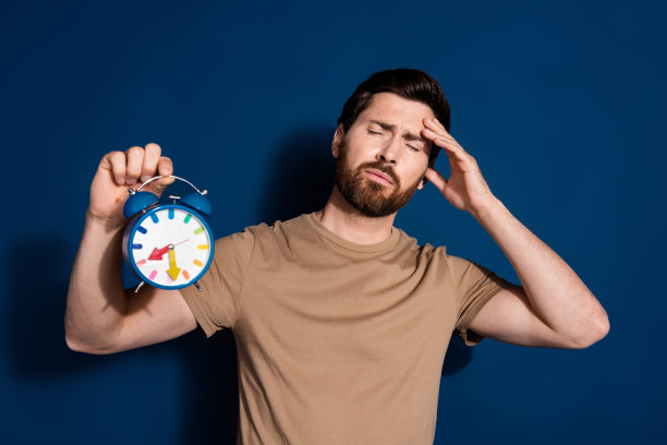 成熟年龄的照片肖像深色胡子有趣的男人在米色t恤触摸额头不喜欢早晨孤立的深蓝色背景图片下载