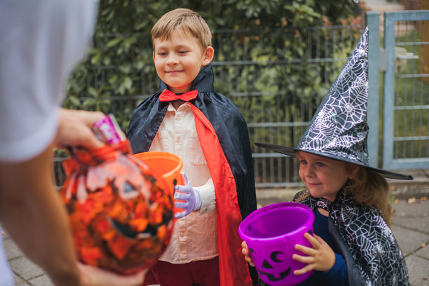 可爱的男孩和女孩打扮成女巫和德古拉拿着南瓜桶图片下载