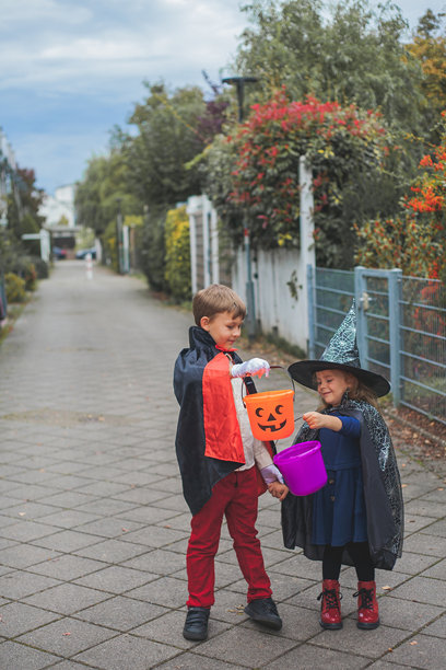 可爱的男孩和女孩打扮成女巫和德古拉拿着南瓜桶图片下载
