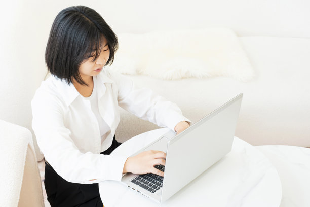 年轻的亚洲女性在她的公寓顶楼上用笔记本电脑打字，在家工作的概念。图片下载