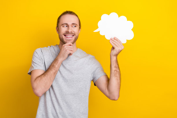 照片中有魅力的头脑男人穿着灰色时尚的衣服，手臂触摸脸，看起来空间空旷，云元素孤立在黄色背景上图片下载