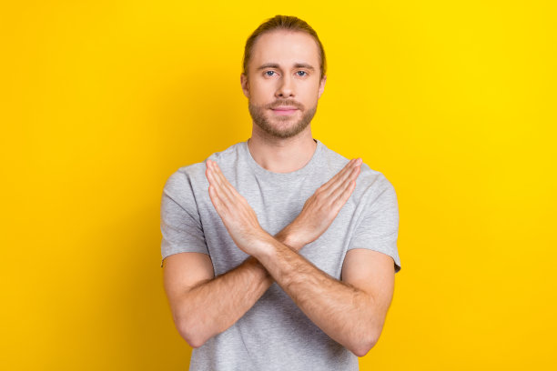 照片中，自信的酷男人穿着灰色t恤，双臂交叉，没有孤立的黄色背景图片下载