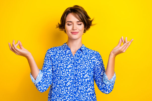 照片肖像迷人的年轻女子闭上眼睛练习冥想穿着时髦的印花服装孤立的黄色背景图片下载
