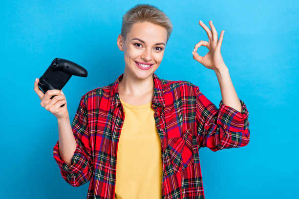 年轻学生女孩的照片肖像，金色短发，穿着红色格子衬衫，展示ok的标志，建议在蓝色背景上孤立的电子游戏图片下载