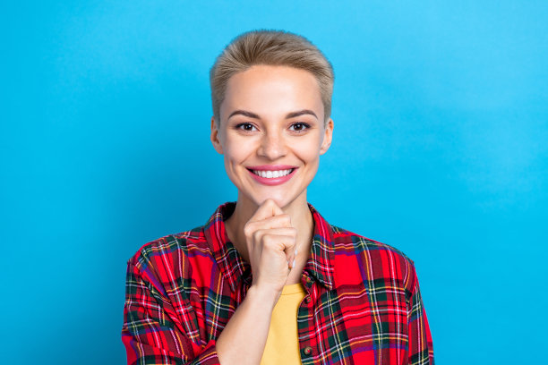 肖像照片开朗积极的女人触摸下巴，体贴聪明的女士穿着红色格子衬衫享受她的生活方式孤立的蓝色背景图片下载