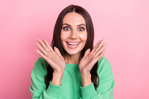 照片中的乐观印象深刻的女人，直发，穿着绿色运动衫，惊讶的盯着孤立的粉红色背景图片下载