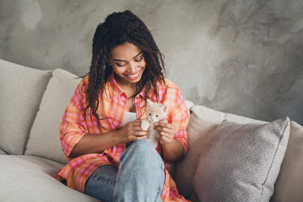 穿着格子衬衫的漂亮开朗的女士在房间里享受治疗小猫的照片图片下载