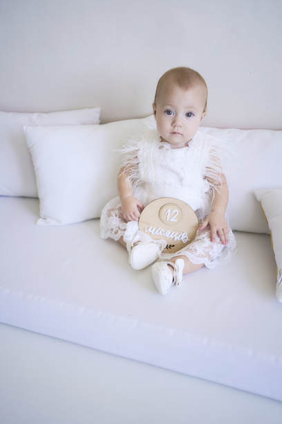 一名女婴一岁生日的照片，婴儿抱饰上用乌克兰语写着“12个月”图片下载