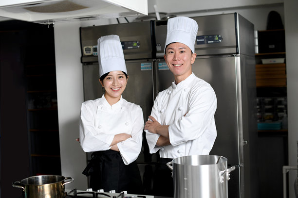 年轻的亚洲女厨师和男厨师在厨房里手挽手图片下载