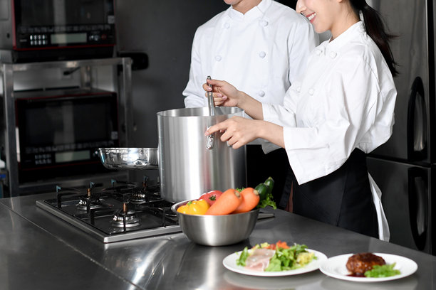 年轻的亚洲女厨师和男厨师正在厨房做饭图片下载