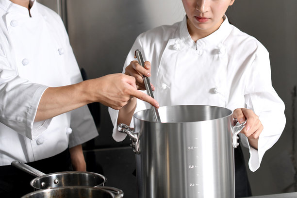 年轻的亚洲女厨师和男厨师正在厨房里聊天图片下载