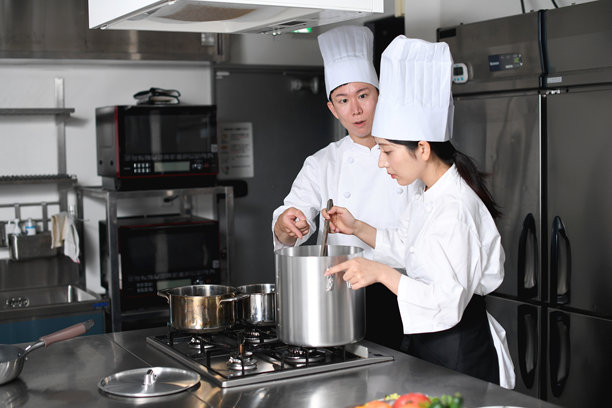 年轻的亚洲女厨师和男厨师正在厨房里聊天图片下载