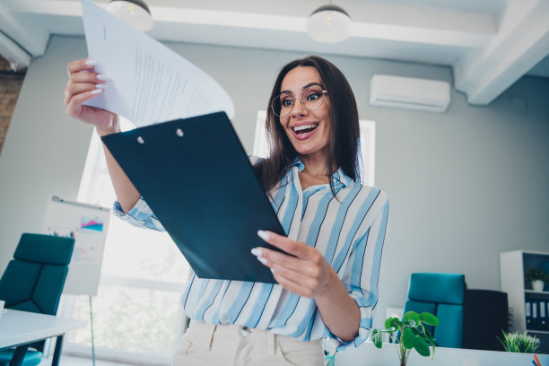 漂亮女人的照片激动地拿着文件袋报告穿着条纹正装舒适的光启动办公室室内图片下载