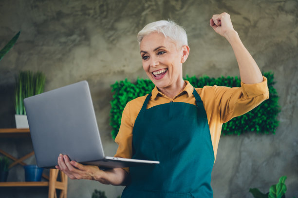 心情好幸运的老年妇女穿着围裙护理鲜花在室内装置喜欢的房子工作场所的照片图片下载