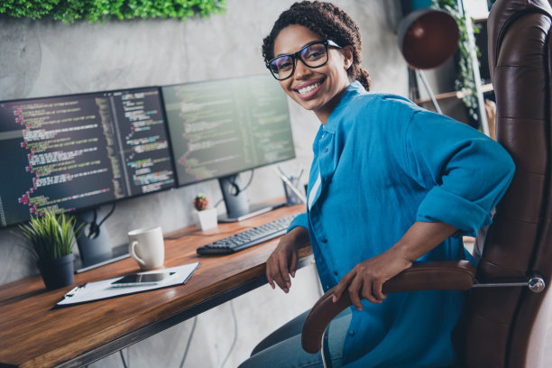 迷人的年轻女子坐在扶手椅上的照片，它的开发人员穿蓝色衬衫现代办公室程序员阁楼房间室内室内工作空间图片下载