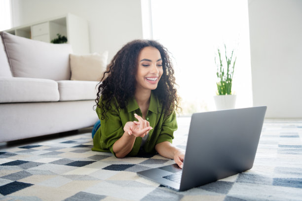 可爱可爱的开朗女孩躺在地毯上客厅讲现代无线上网本公寓室内的照片图片下载
