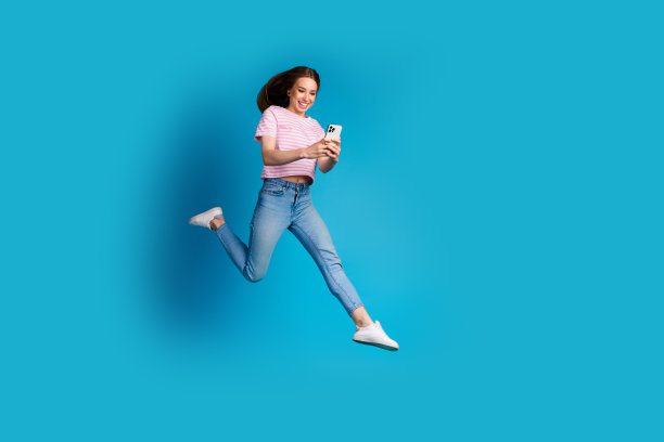 可爱的年轻女士跑步的全身照片，穿着时尚的粉红色条纹服装，孤立在蓝色背景上图片下载