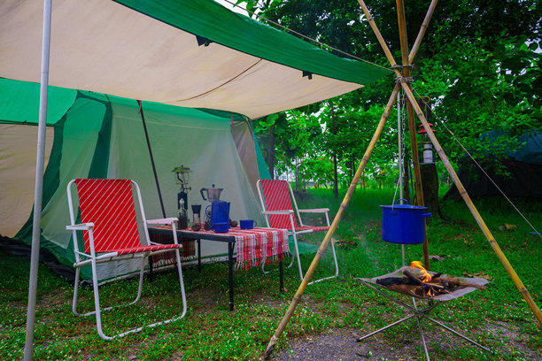 露营帐篷，复古小屋帐篷，古色古香的灯笼，复古的椅子，以及在森林里的木桌上的户外咖啡制作设备图片下载