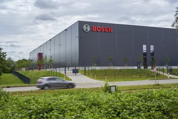 现代博世大厦，汽车在前景中经过，周围环绕着绿色植物，描绘了企业建筑和运动。Wernau，德国，欧洲。图片下载