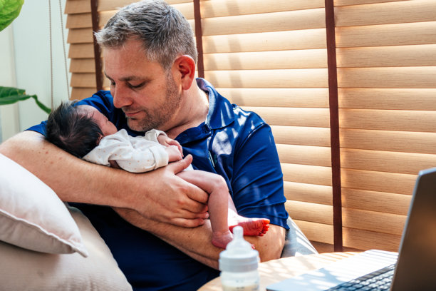 父亲坐在膝上用笔记本电脑工作图片下载